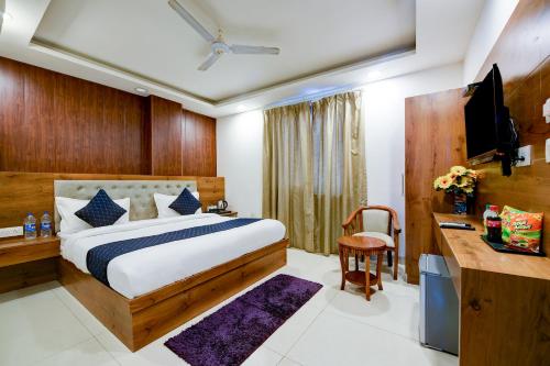 a bedroom with a bed and a desk and a television at Hotel Grand Qubic Near Delhi Airport in New Delhi
