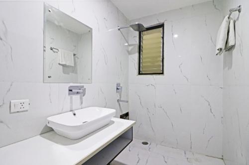 a white bathroom with a sink and a mirror at Hotel Grand Qubic Near Delhi Airport in New Delhi