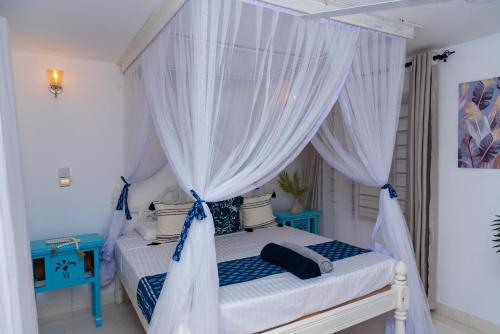 a bedroom with a canopy bed with white curtains at Malindi Palm Villa- Harbour Key Cottages, Villa 16, Silver Sands Road in Malindi