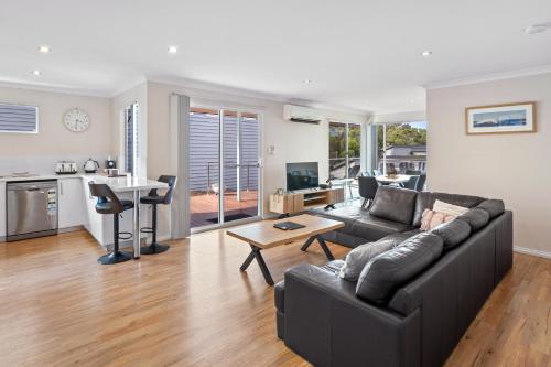 a living room with a black couch and a kitchen at Surfs Up in Dunsborough
