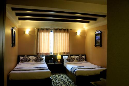 a bedroom with two beds and a window at Hotel Garuda in Bhaktapur