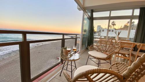 ein Balkon mit Tisch und Stühlen und der Strand in der Unterkunft MAR Suites OnlyMalaga in Benalmádena