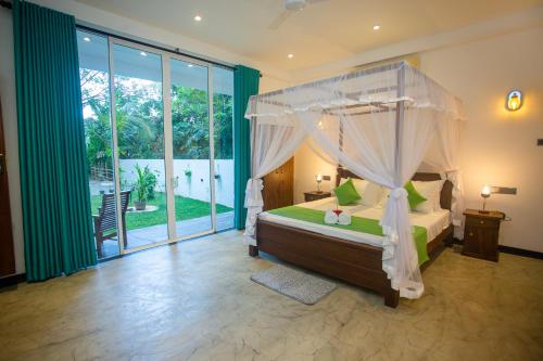 een slaapkamer met een hemelbed en een groot raam bij Villa Nine84 Mirissa in Matara