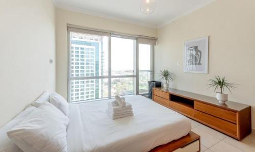 a bedroom with a large bed and a large window at Manzil - 1BR in Fairways West with Golf Course View in Dubai