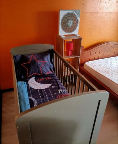 Cuna en habitación con cama y ventilador en Case créole en Saint-Pierre