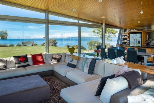 a living room with a large couch and a large window at Kina Retreat - Luxury Nelson Getaway in Tasman