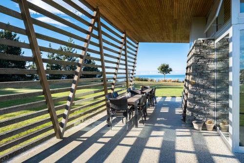a patio with tables and chairs on a house at Kina Retreat - Luxury Nelson Getaway in Tasman