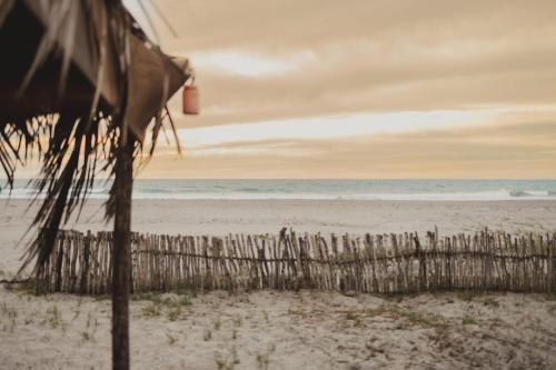 a fence on the beach with the ocean in the background at Tres Velas Surf in Celestino Gasca