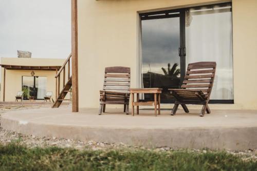 two chairs and a table in front of a house at Tres Velas Surf in Celestino Gasca