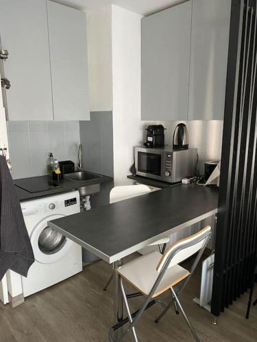une cuisine avec une table et une machine à laver dans l'établissement studio hyper centre ville et gare, à Strasbourg