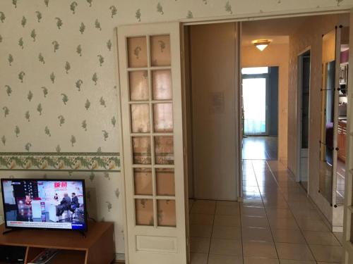 un couloir avec une pièce avec une télévision et un mur dans l'établissement Grand Appartement proche d’Orly et Paris, à Ris-Orangis