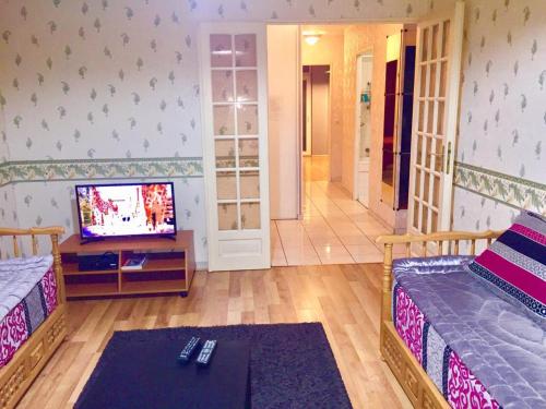 uma sala de estar com duas camas e uma televisão em Grand Appartement proche d’Orly et Paris em Ris-Orangis
