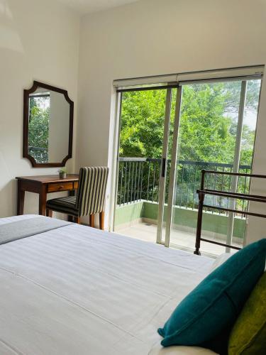 a bedroom with a bed and a view of a balcony at Hideout Ariyana in Athurugiriya