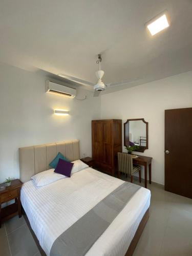 a bedroom with a large white bed and a mirror at Hideout Ariyana in Athurugiriya