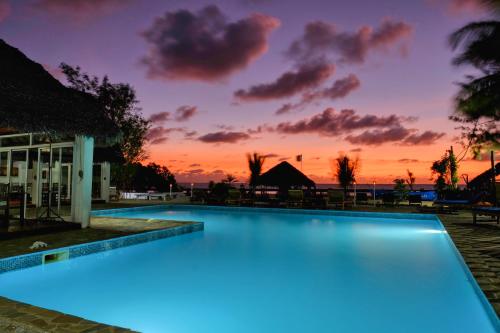 a swimming pool with a sunset in the background at Le Moya Beach in Nosy Be