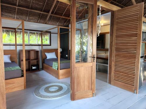 Tua PejatにあるLeleu Mentawai Accommodationのベッド2台とドア付きの部屋1室を利用します。