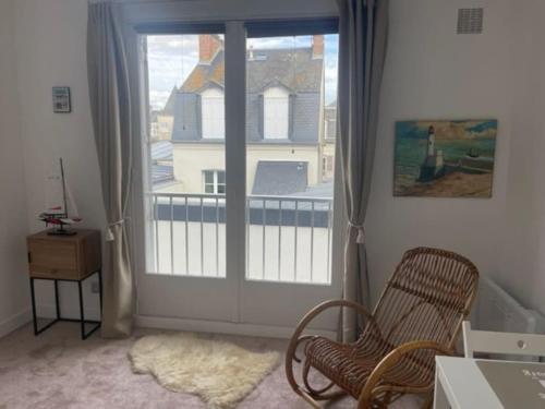 Cette chambre dispose d'une fenêtre avec une chaise et d'un balcon. dans l'établissement Studio hypercentre Villers-sur-Mer, à Villers-sur-Mer
