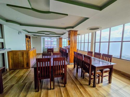 達旺鎮的住宿－Hotel Kimnas，用餐室设有木桌、椅子和窗户。