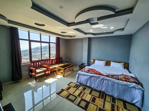 a bedroom with a bed and a large window at Hotel Kimnas in Tawang