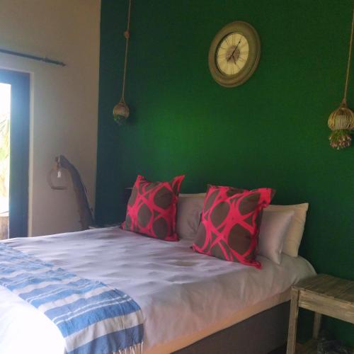 a green bedroom with a bed with red pillows at Patogeng Self Catering - Da Gama Dam view in White River