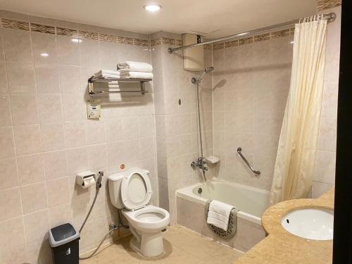 a bathroom with a toilet and a tub and a sink at Gold Orchid Bangkok Hotel in Bangkok