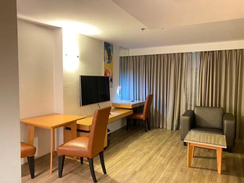 a hotel room with a desk with a television and chairs at Gold Orchid Bangkok Hotel in Bangkok