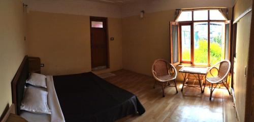 a bedroom with a bed and two chairs and a window at Alifland in Srinagar