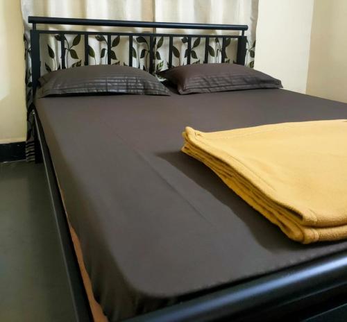 a black bed with a yellow blanket on it at Patil Homestay AC in Belgaum