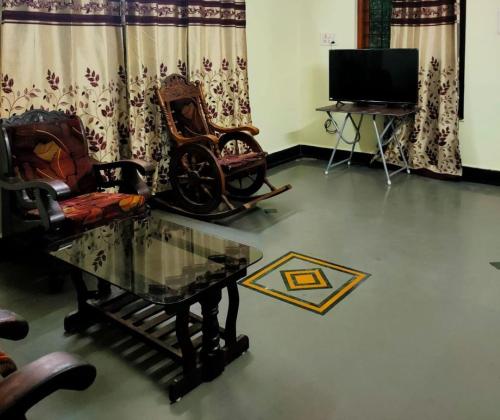 a living room with chairs and a table and a tv at Patil Homestay AC in Belgaum