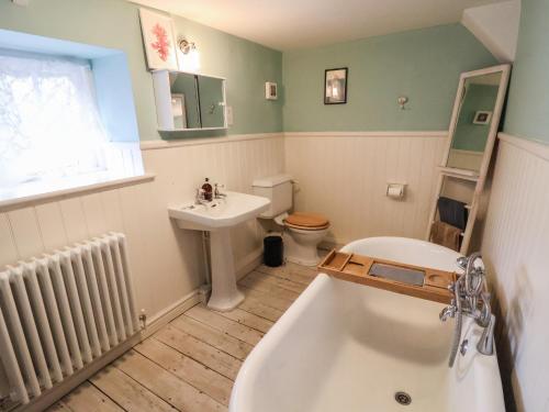 y baño con bañera, aseo y lavamanos. en Post Office Cottage en Weymouth