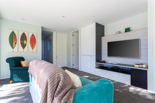 a living room with a blue couch and a tv at Kina Retreat - Luxury Nelson Getaway in Tasman
