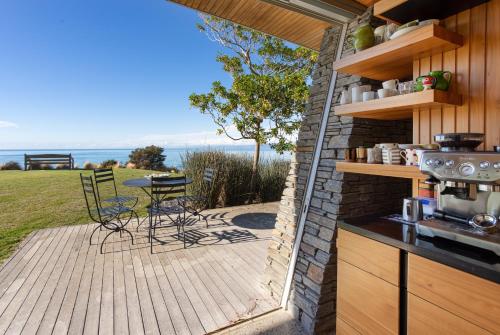 a patio with a table and chairs on a deck at Kina Retreat - Luxury Nelson Getaway in Tasman