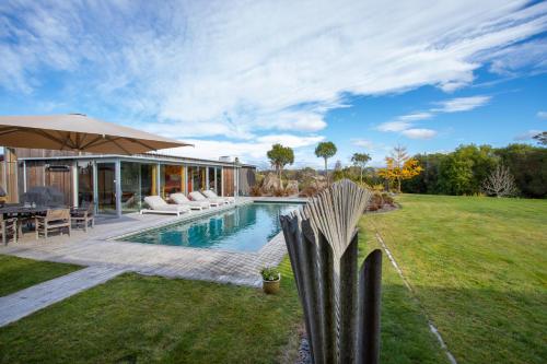 a backyard with a swimming pool and a house at Kina Retreat - Luxury Nelson Getaway in Tasman