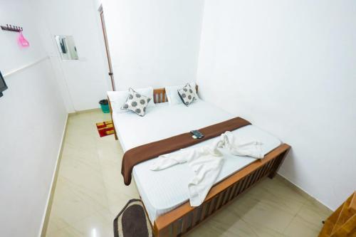 um quarto com uma cama com lençóis brancos e almofadas em SIYA RESIDENCY em Ernakulam