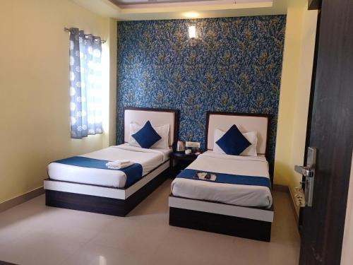 een slaapkamer met 2 bedden en een blauwe muur bij Hotel Janki International Sigra 2 KM From Kashi Vishwanath Temple in Varanasi