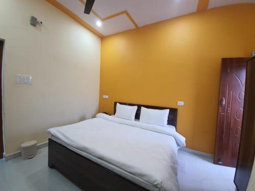 Butola Hotels في ريشيكيش: غرفة نوم بسرير كبير وبجدار اصفر