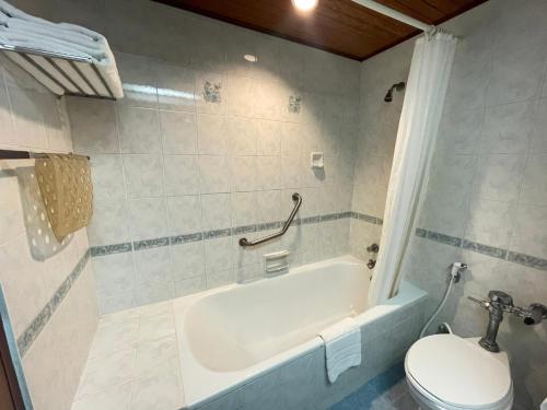 a bathroom with a white tub and a toilet at Wangcome Hotel in Chiang Rai