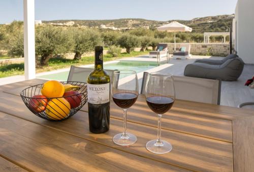 due bicchieri di vino e un cesto di frutta su un tavolo di Anthelia Luxury Villas a Karpathos