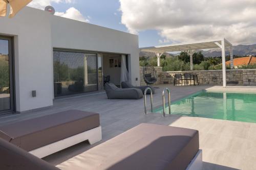 a house with a swimming pool and a patio at Anthelia Luxury Villas in Karpathos Town