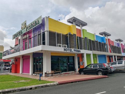 un bâtiment coloré avec des voitures garées devant lui dans l'établissement Hotel Prima, à Sandakan