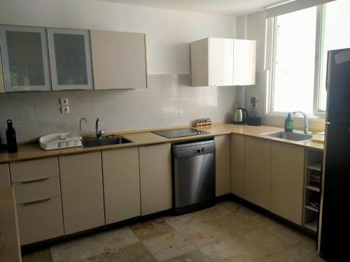 a kitchen with white cabinets and a sink and a dishwasher at Espace et sérénité in Netanya