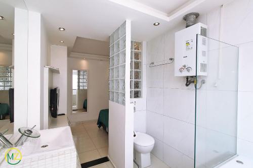a white bathroom with a toilet and a sink at Moderno Apto 3 suites p/ 8 pessoas em Copacabana in Rio de Janeiro