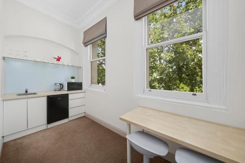 a kitchen with a desk and two windows at Clarendon Hotel in Melbourne