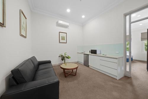 a living room with a black couch and a desk at Clarendon Hotel in Melbourne