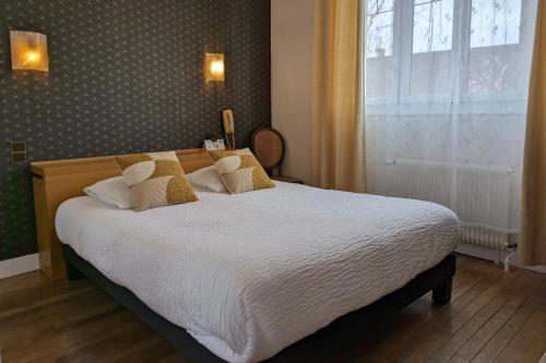 a bedroom with a bed with white sheets and a window at Logis Hôtel Le Saint Florent in Mont-près-Chambord