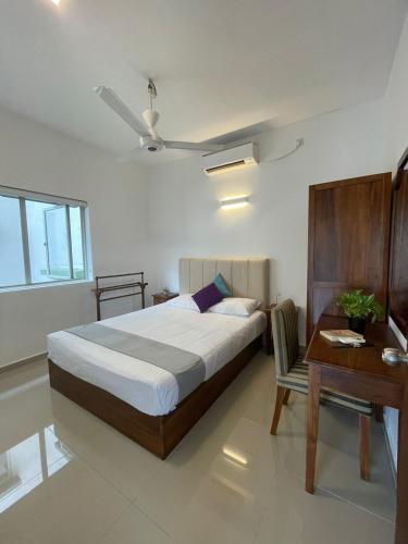 a bedroom with a bed and a table and a desk at Hideout Ariyana in Athurugiriya