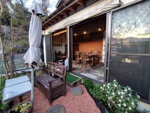 a patio with an umbrella and a table and chairs at Pension Izukogen in Ito
