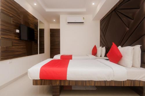 OYO Flagship Hotel Park Palace في مومباي: غرفة نوم بسرير كبير ومخدات حمراء