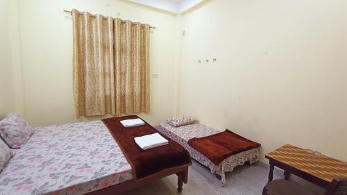 a bedroom with two beds and a table and a window at ARJUN PAYING GUEST HOUSE in Ayodhya