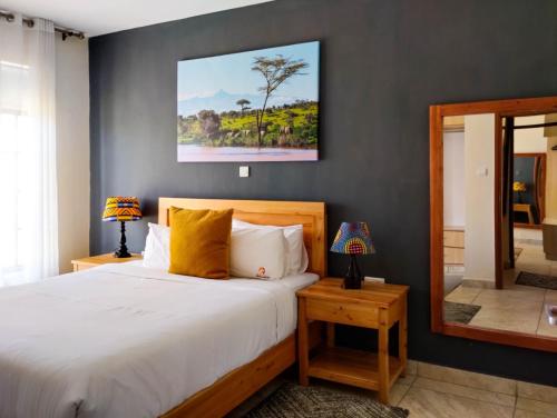 - une chambre avec un grand lit et un miroir dans l'établissement Swara Ranch Nanyuki, à Nanyuki